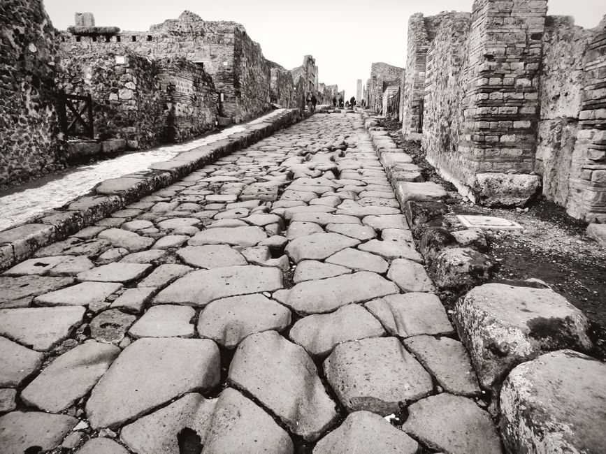 Explore the preserved ancient cobblestone street in Pompeii, Italy, showcasing Roman architecture.