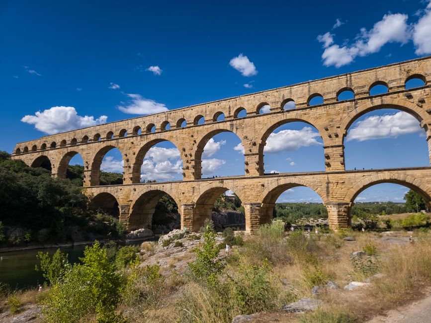 The Pont du Gard aqueduct, a Roman architectural marvel, against a clear blue sky in Nîmes, France.