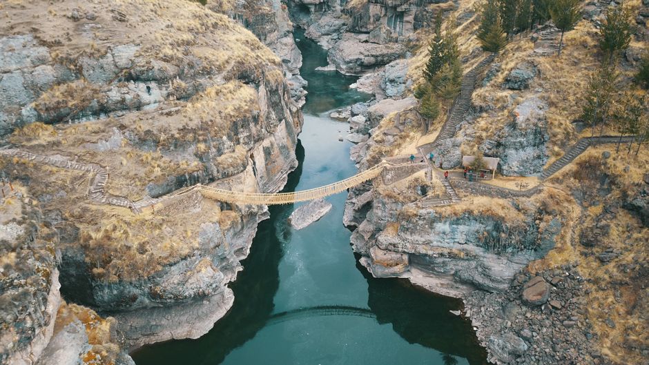Stunning aerial shot of the Qeswachaka Rope Bridge spanning a river gorge in Cuzco, Peru.